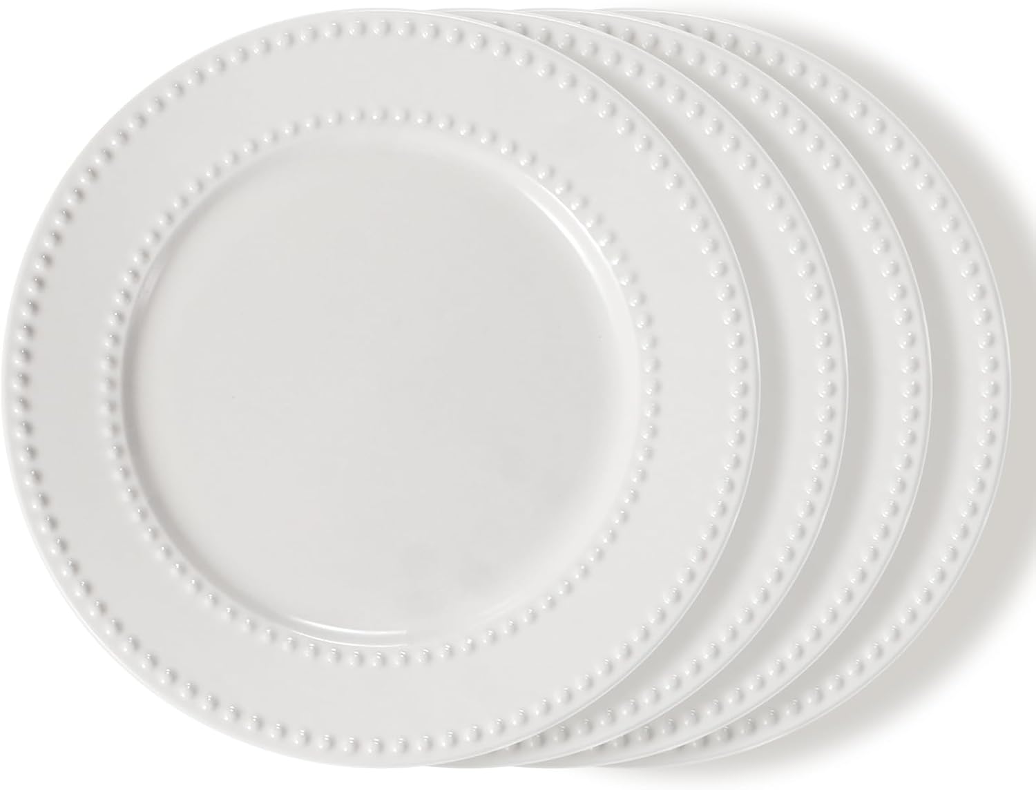 Four stacked white plates with a raised dot pattern around the edges, shown on a plain white background—perfect for serving a slice of pink lemonade pie.