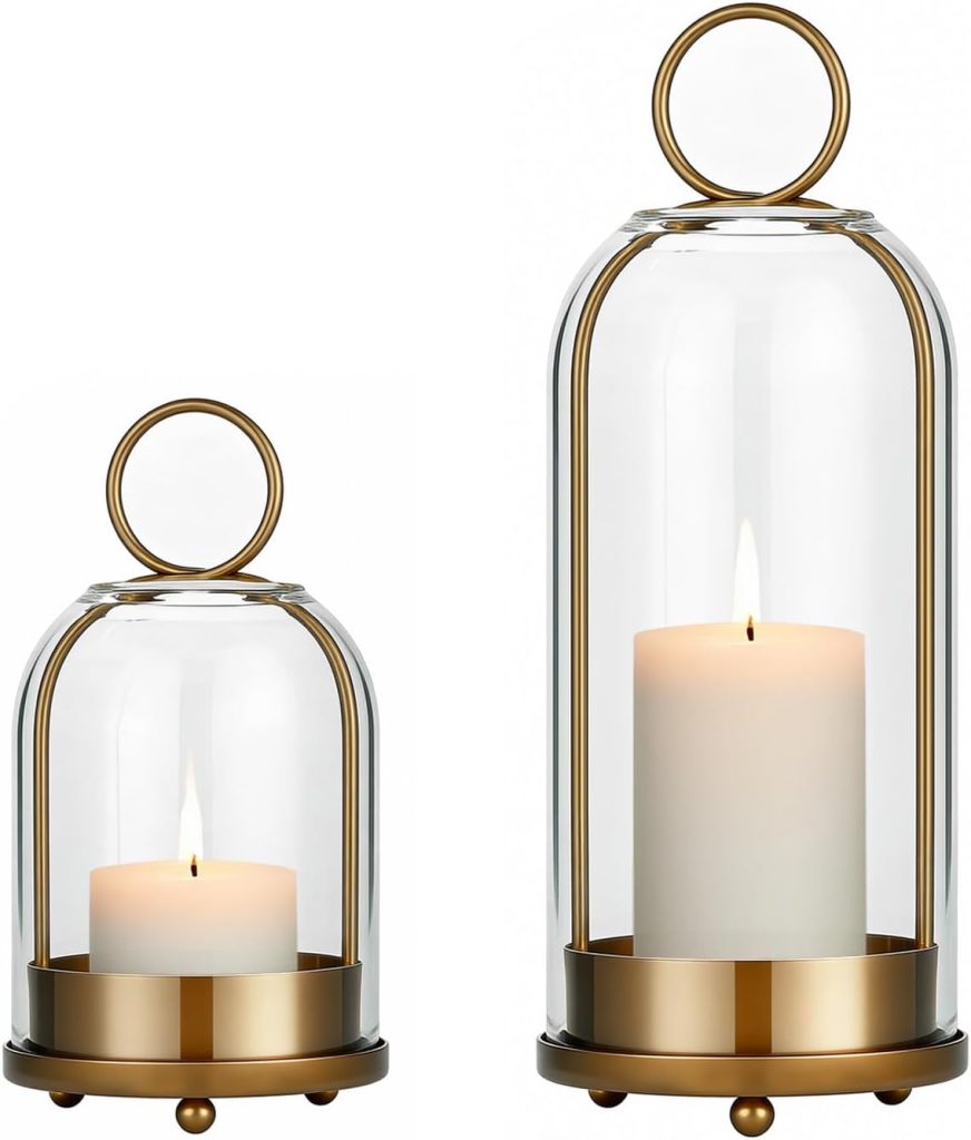Two glass hurricane candle holders with gold metal bases and circular handles, each containing a lit white pillar candle. The holders, one smaller than the other, are delicately adorned with pressed flowers for a charming touch.