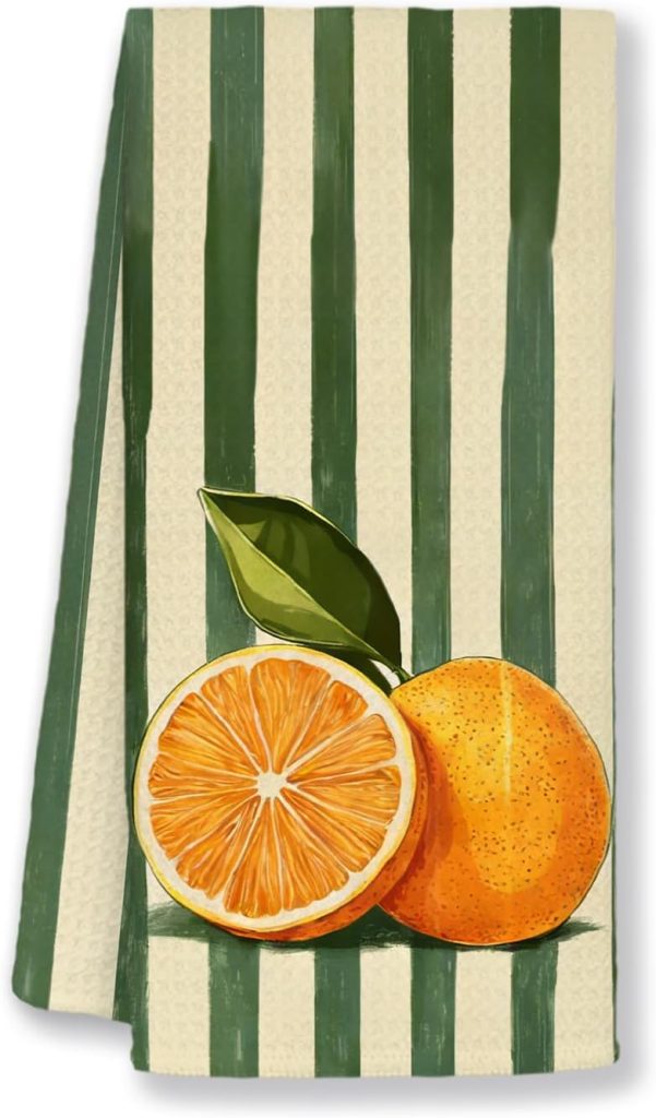 A striped towel with a printed design featuring a whole orange and a half orange with a leaf in front of green and beige vertical stripes.