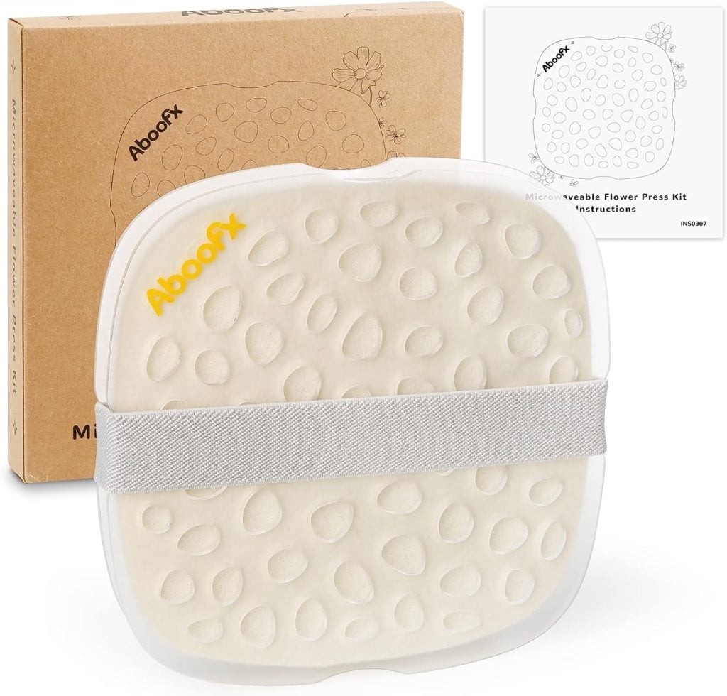 A reusable flower press kit with a textured white surface, perfect for making pressed flowers, secured by a gray elastic band and shown with its instruction manual and brown cardboard box.