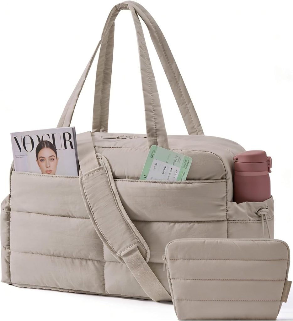 Beige quilted duffel bag with a magazine, travel documents, and a pink bottle in its pockets, plus a matching zip pouch in front.