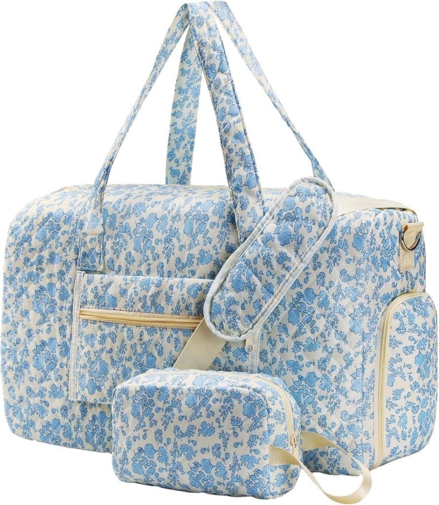 Three matching travel bags with blue floral patterns, including a large duffel, a small zip pouch, and a long strap, arranged against a white background.