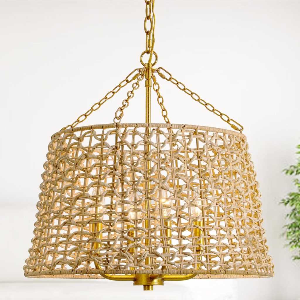 A woven rattan chandelier with gold chain supports hangs from the ceiling, echoing the natural textures often found in rattan furniture. Four light bulbs are visible inside the shade, while a green plant is blurred in the background.