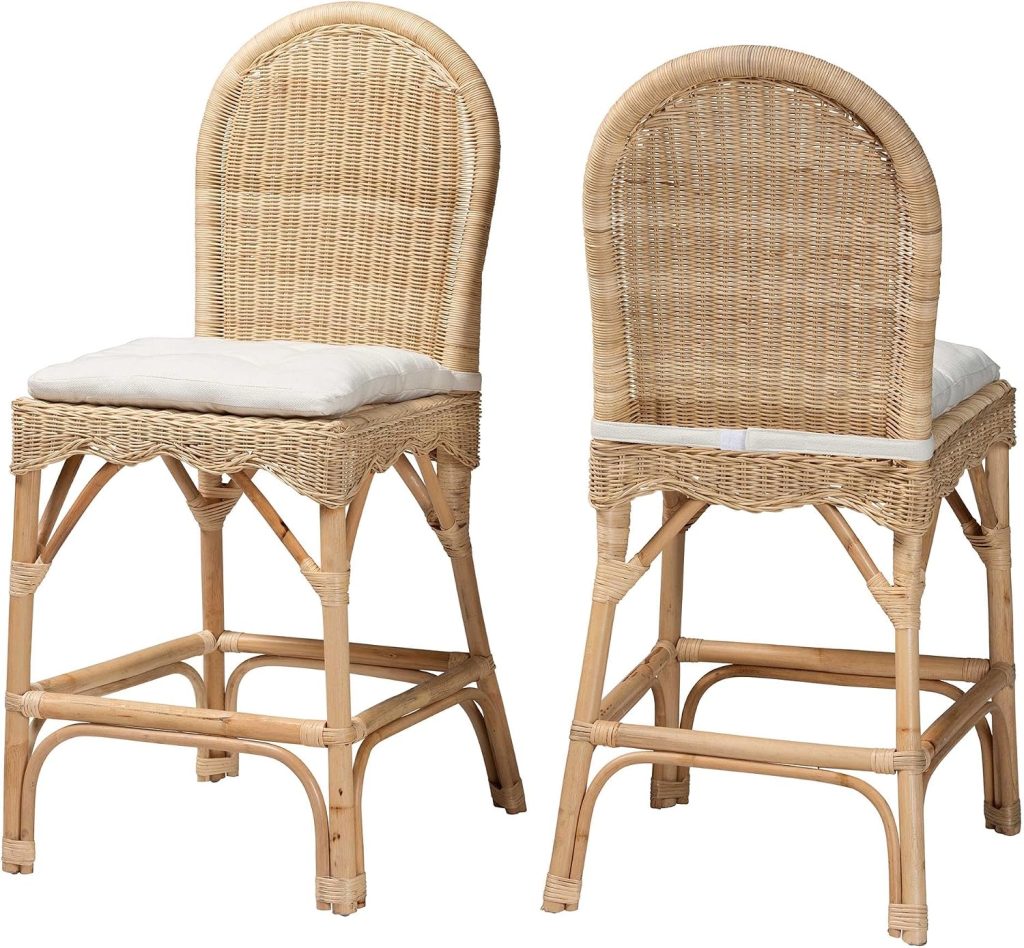 Two rattan bar stools with arched backs and white seat cushions are positioned side by side, one facing forward and the other facing backward, showcasing the versatility and charm of rattan furniture.