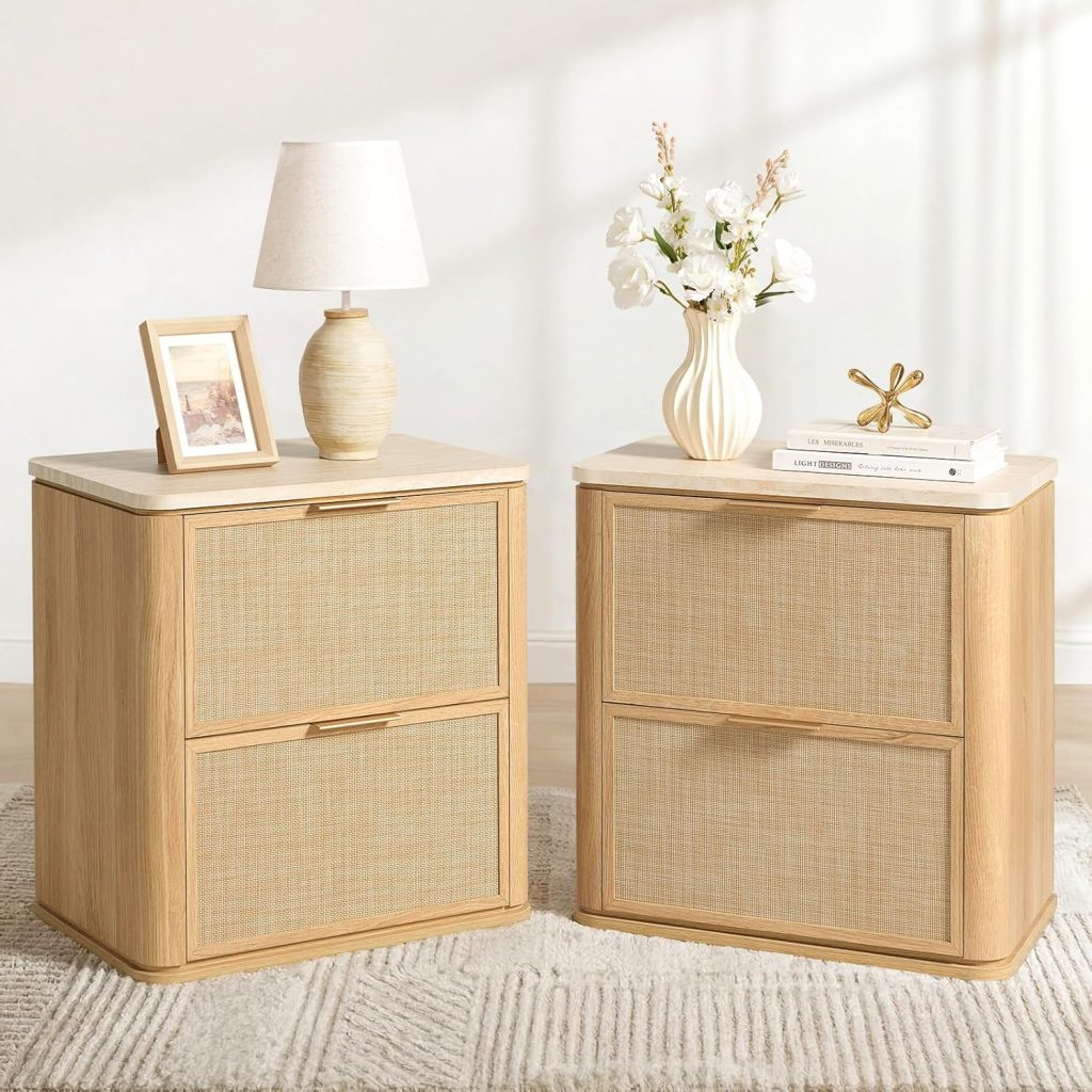 Two light wood nightstands with woven rattan drawer fronts add a touch of rattan furniture charm; one holds a lamp and framed photo, while the other displays a vase with flowers, books, and a decorative object. Both sit atop a beige rug.