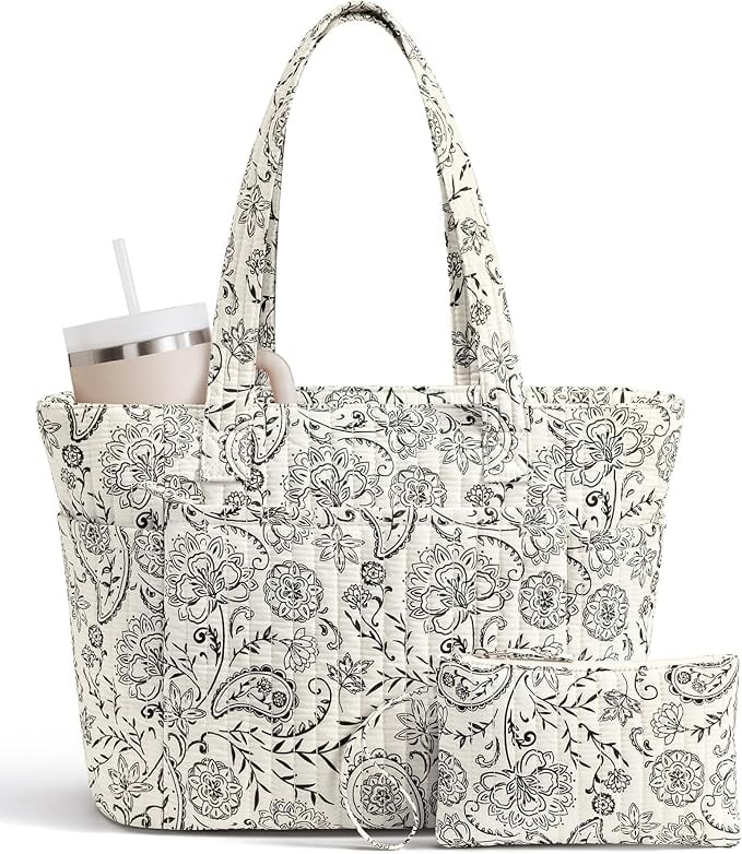 A white quilted tote bag with black floral patterns, matching zipper pouch, and a tumbler with a straw in an exterior pocket.