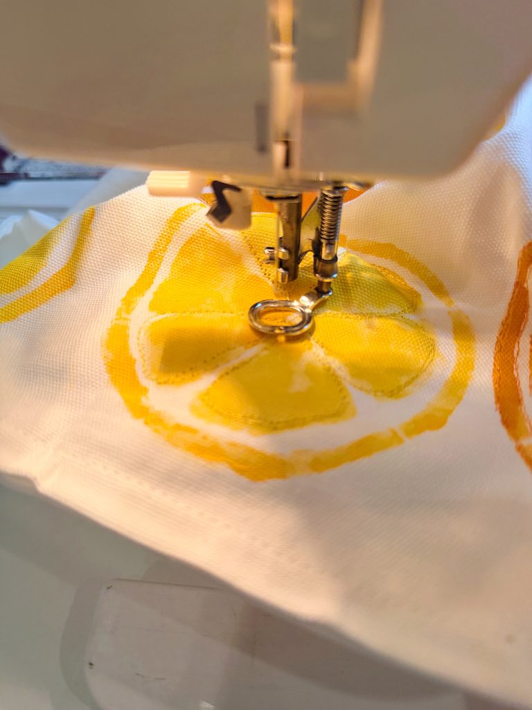 Close-up of a sewing machine stitching yellow lemon slice fabric.