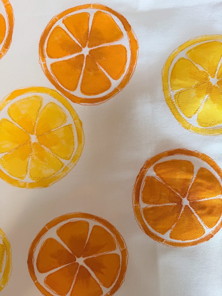 Pattern of orange and yellow citrus slices on a white background. The slices are arranged without overlapping and have a hand-painted style.