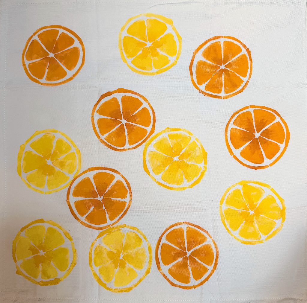 A white cloth features a pattern of orange and yellow citrus fruit slices scattered evenly across the surface.