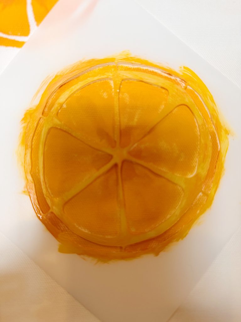 A painted orange slice with eight segments is seen on a white surface, resembling a citrus fruit viewed from above.