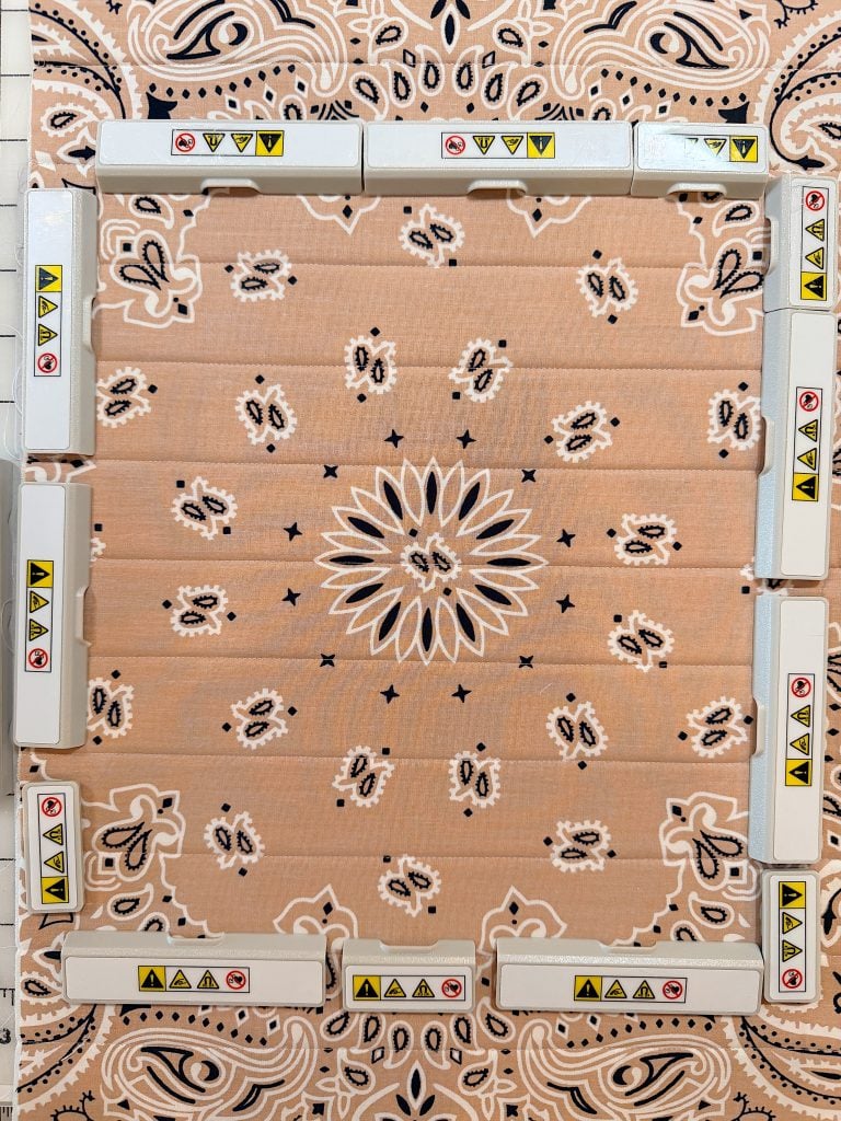Rectangular arrangement of white plastic objects with yellow and red caution symbols on a beige patterned cloth with black and white designs.