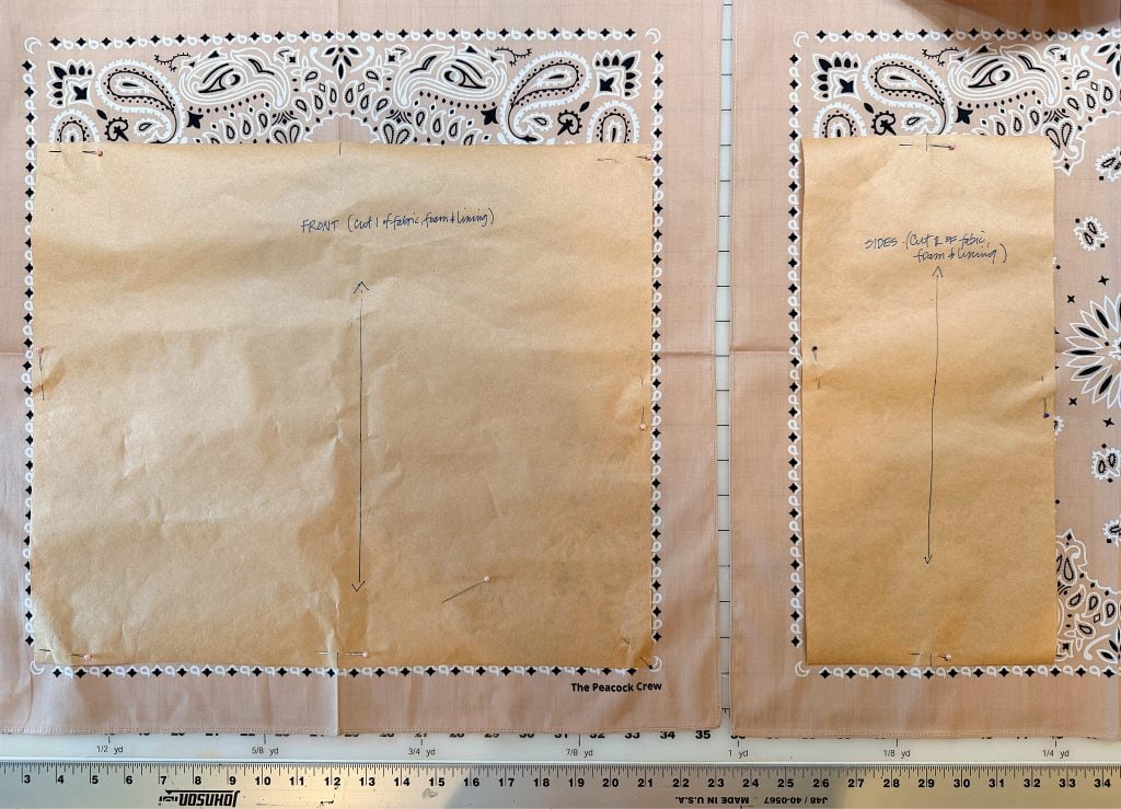 Two paper sewing patterns labeled "FRONT" and "SIDE" are pinned to bandana fabric, with a ruler at the bottom edge and grid cutting mat underneath.